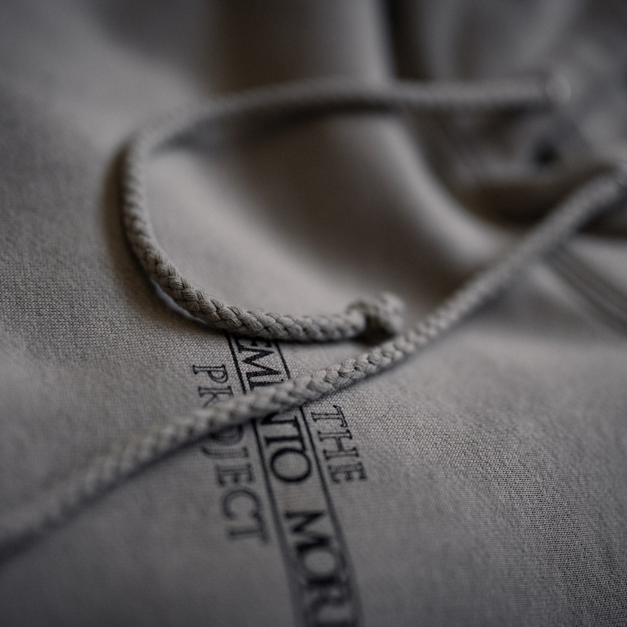Close-up of a gray hoodie with text on the fabric.
